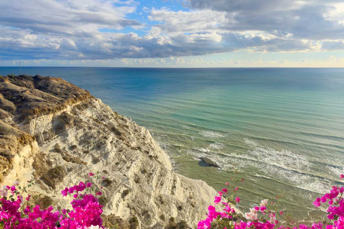 Interno del traghetto con persone che guardano il mare, auto parcheggiate e scorcio della costa di Pantelleria all’orizzonte. Atmosfera di viaggio.