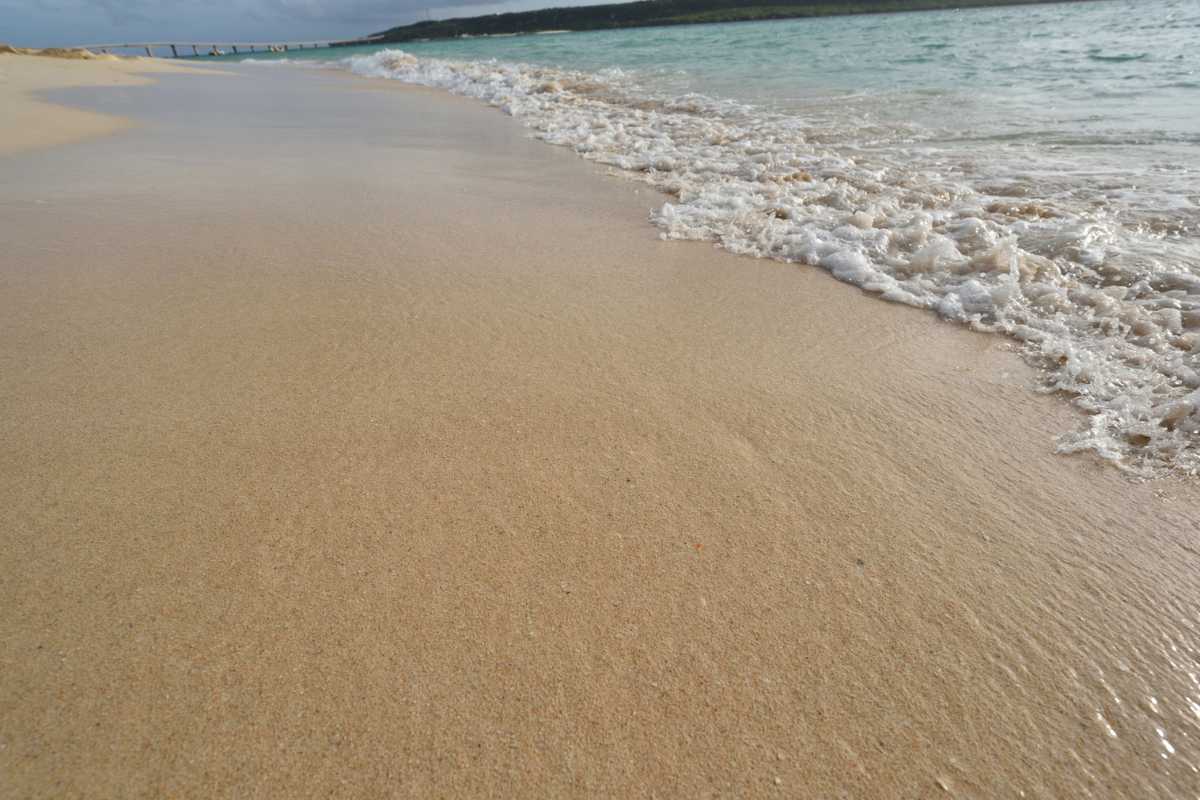 Famiglia con bambini che gioca sulla spiaggia di sabbia dorata di Pantelleria, acqua bassa e limpida, atmosfera serena, giochi da spiaggia