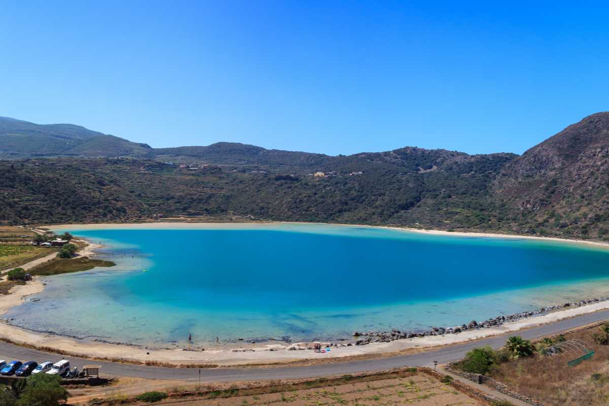 Escursionisti che camminano sul cratere della Montagna Grande, con vista sul Lago di Venere e mare di Pantelleria